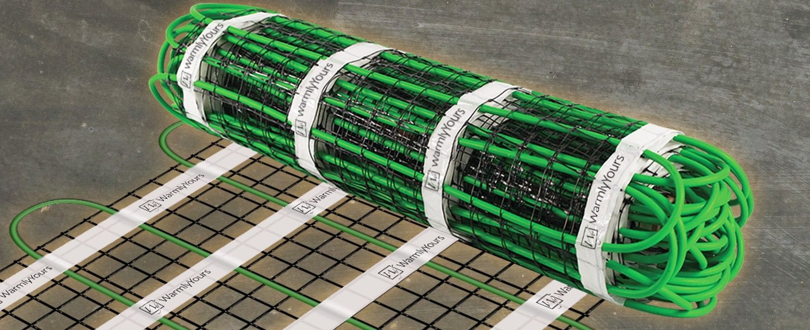 Snow melting mat rolled out over a mesh on grey pavement, the WarmlyYours name printed on the mat tapes